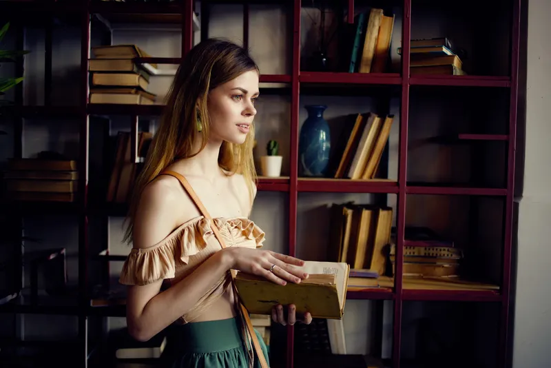 Красивая женщина с книгой в руках отдыхает в кафе
