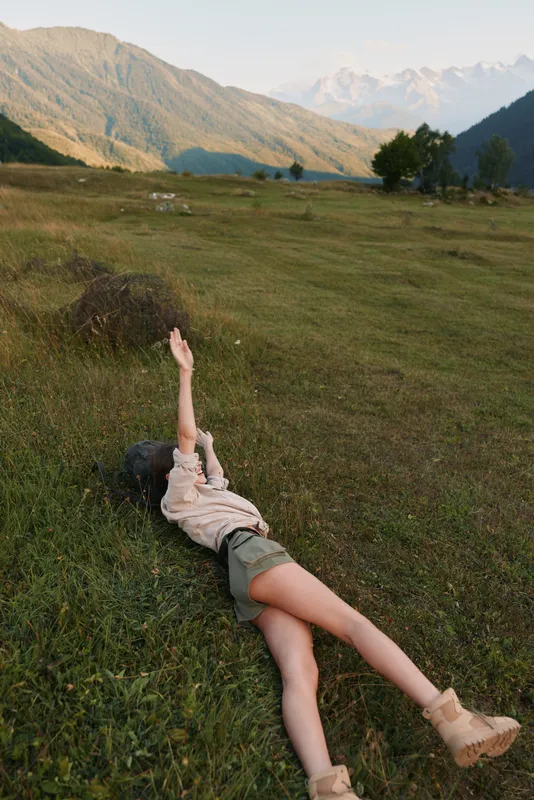 A woman lifestyle outdoor nature meadow landscape relaxation hiking vacation freedom in a grassy field with distant mountains, a candid moment of calm and serenity.