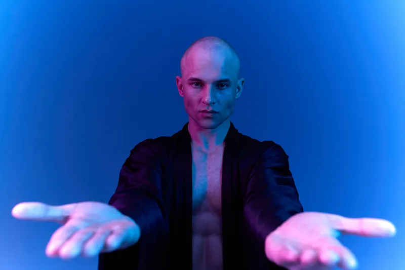 Handsome man with an open gesture, conveying a sense of calm and welcoming energy in a vibrant blue lighting. This image embodies tranquility and connection.