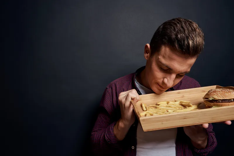 Мужчина держит деревянный поднос с фастфудом