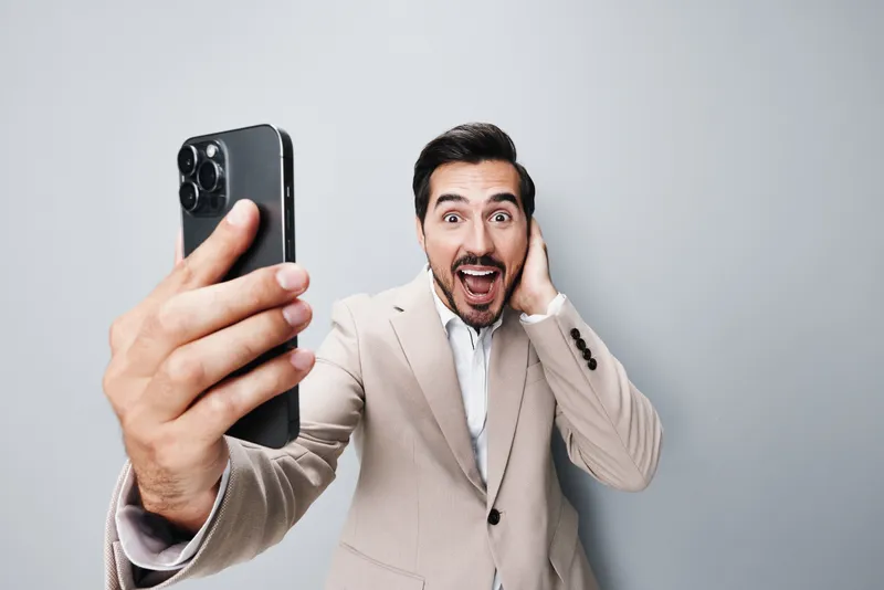 Мужчина держит смартфон, делая селфи