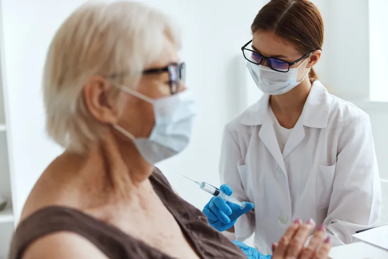 Женщина-врач делает инъекцию шприцем для вакцинации, на фоне паспорта и больницы