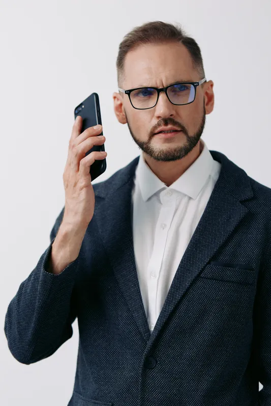 Professional businessman on an isolated colored background, holding a phone and looking focused, delivering a confident, proactive moment with calm determination.