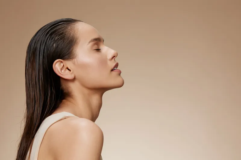 Elegant portrait of a serene woman with wet hair against a neutral background, embodying beauty and tranquility in a minimalist style