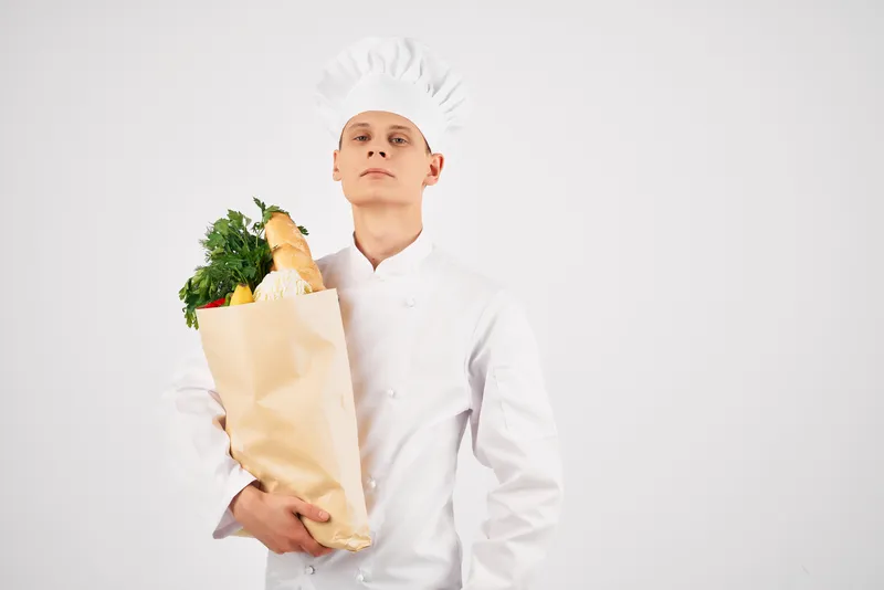 Весёлый мужчина-шеф-повар с упаковкой продуктов на кухне
