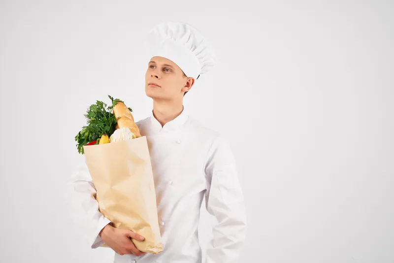Весёлый шеф-повар мужского пола с упаковкой полезных продуктов питания, предоставляющий услуги на кухне