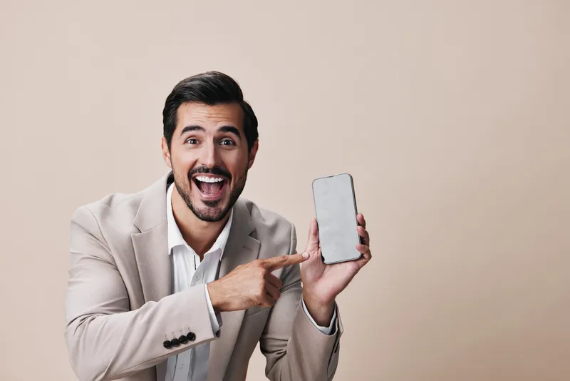 Мужчина в деловом костюме держит смартфон и улыбается, делая селфи