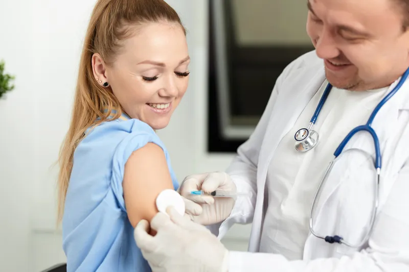 Врач-мужчина делает пациенту укол вакцины