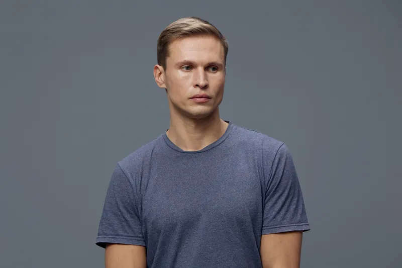Thoughtful young caucasian man wear casual blue t-shirt look sideways isolated on solid gray background studio portrait digital detox concept