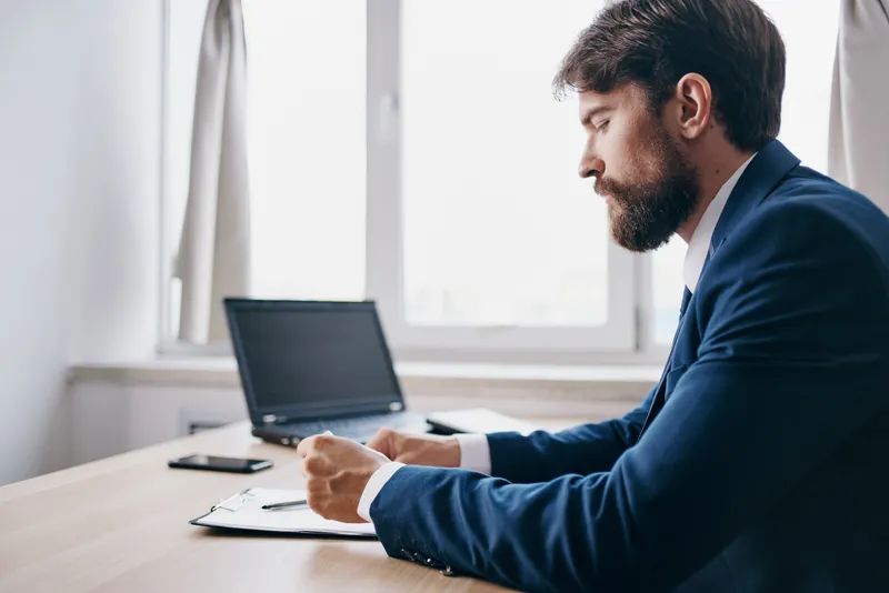 Менеджер работает за ноутбуком в офисе, испытывая официальные эмоции
