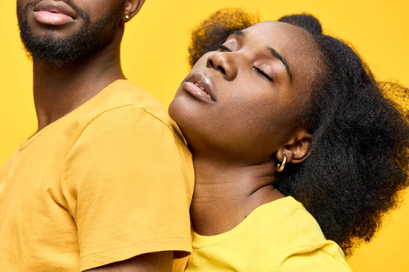 African couple in matching yellow outfits, expressing love and connection against a bright yellow background, symbolizing joy and harmony in relationships