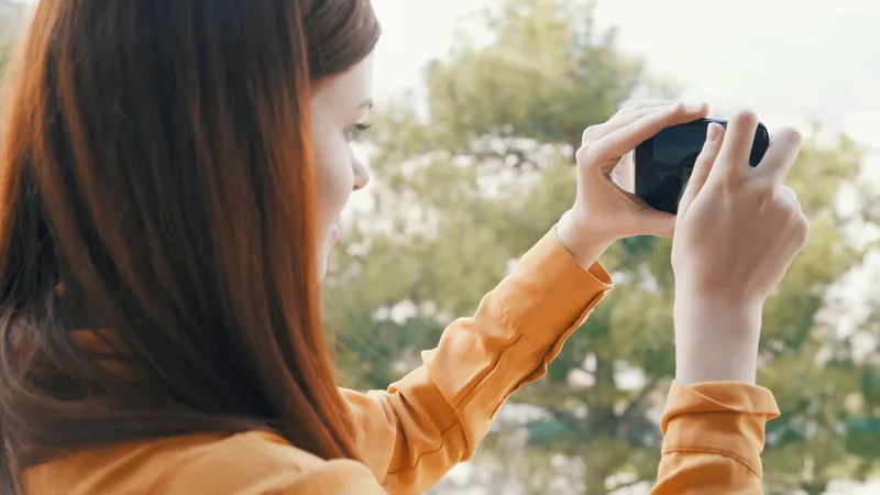 Женщина на улице с телефоном в руках фотографирует природу, панорама, отдых
