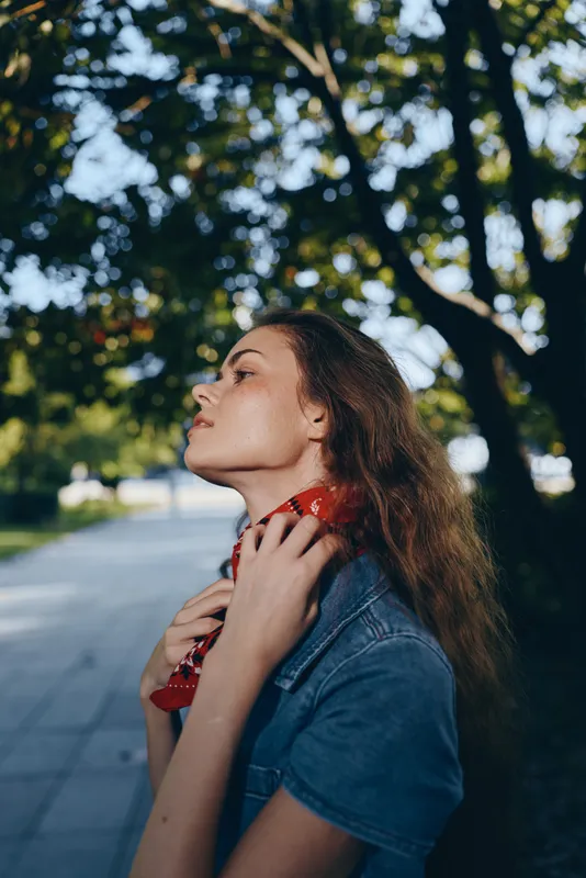 Lifestyle woman in modern boho-western denim street style with a red bandana, captured in warm film color tones under natural outdoor lighting.
