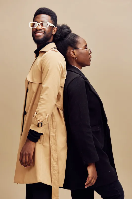 Stylish young diverse models pose back to back in fashionable coats against a neutral background, showcasing modern urban fashion trends and confident emotions