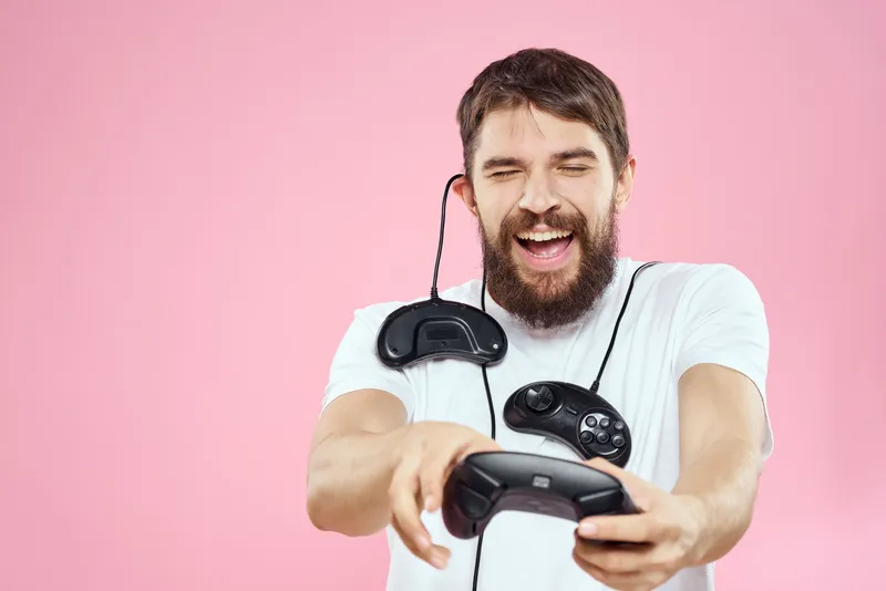 Мужчина с двумя джойстиками в руках, весёлая игра, технологии, образ жизни, розовый фон