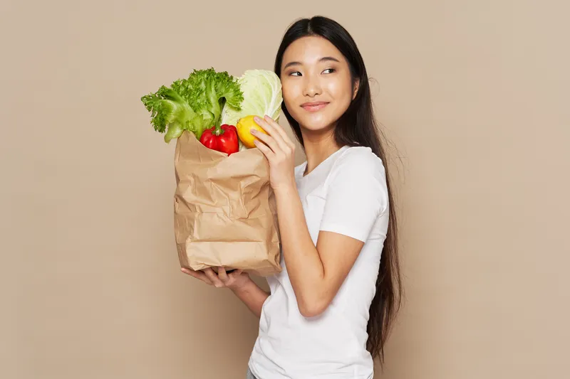 Симпатичная азиатская женщина с пакетом продуктов, занимающаяся домашними делами, овощи, еда, диета