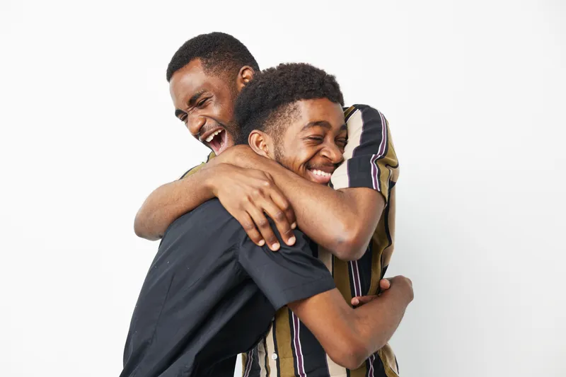 Two joyful African American men share a warm embrace, showcasing happiness and friendship. Their genuine smiles radiate a positive energy that captivates viewers.
