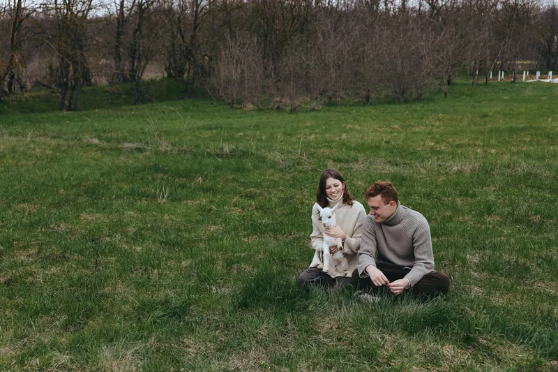 Couple outdoor grass goat kid lifestyle affection nature relaxed candid in a calm field setting, showing warmth and togetherness through a gentle moment outdoors