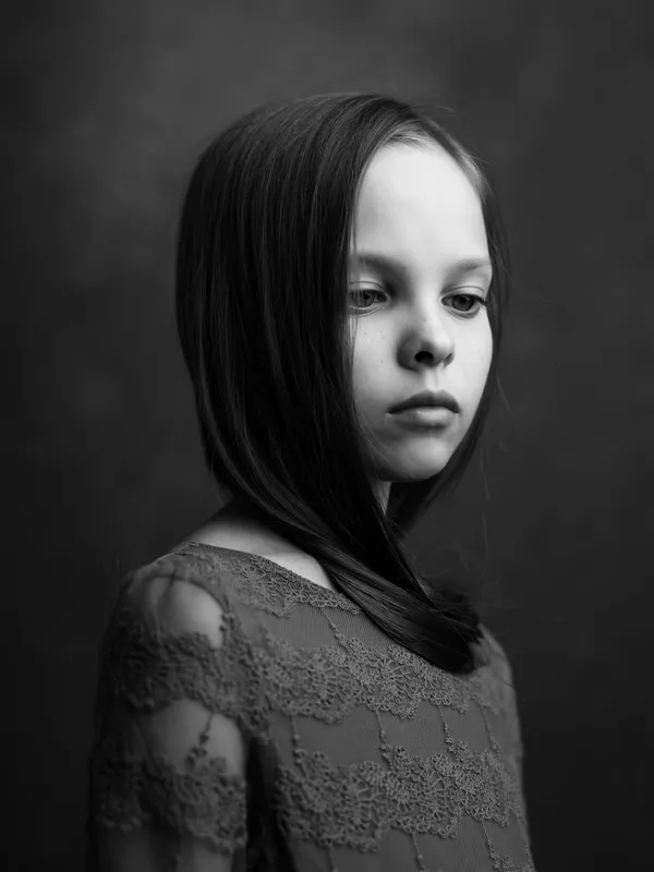 Крупный план черно-белой фотографии маленькой девочки с длинными волосами, которая позирует