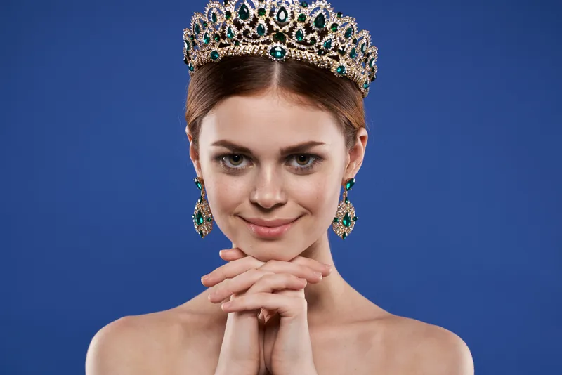 Красивая женщина с обнаженными плечами, украшениями и косметикой, обладающая привлекательным взглядом