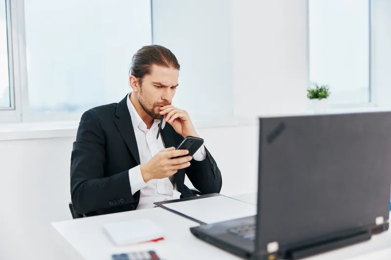 Деловые люди в офисе работают с документами, держа в руке телефон, руководитель