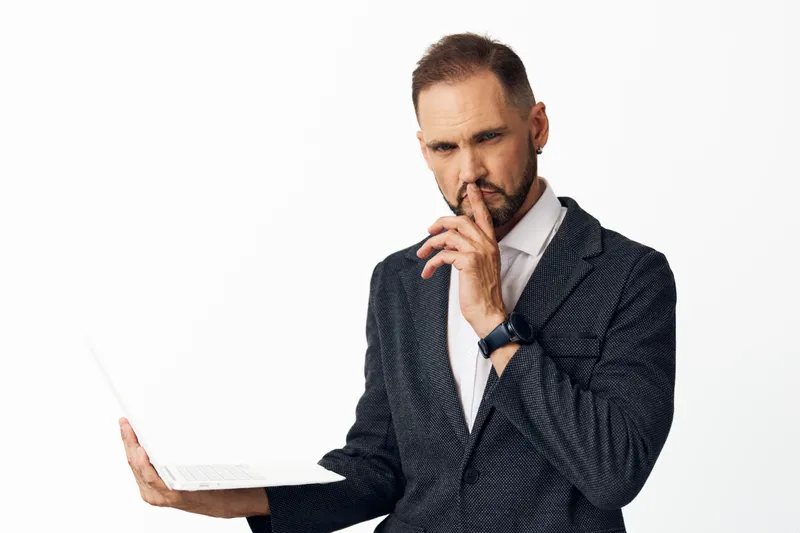 A professional man in a suit stands with a thoughtful expression on an isolated light background, conveying calm focus, strategic thinking, and confident leadership.