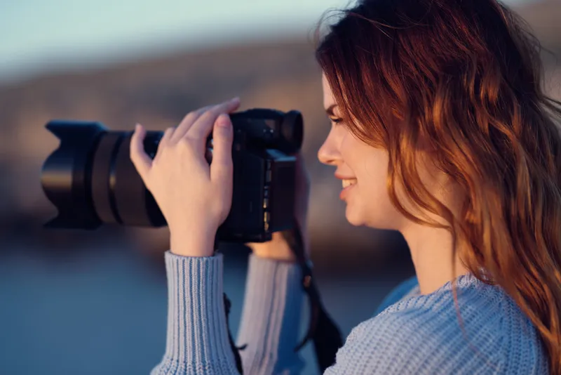 Симпатичная женщина-фотограф путешествует с камерой, снимая пейзаж
