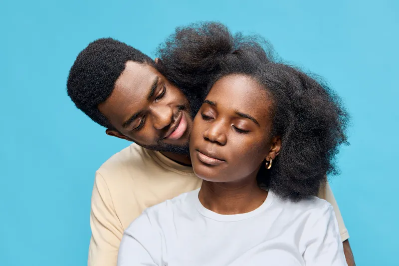 Happy young couple with natural hair against a blue background, showcasing love and connection in a vibrant and modern style