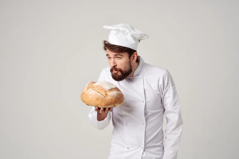 Повар на кухне, работа с хлебобулочными изделиями на светлом фоне