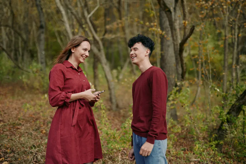 Natural candid portrait of a genuine conversation between two people in a forest clearing, showcasing honest expressions, relaxed body language and a believable everyday connection.