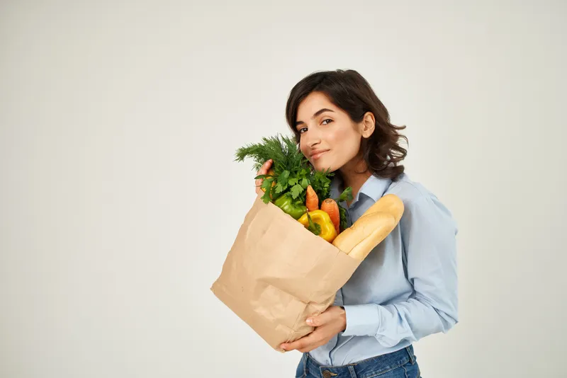Брюнетка с пакетом продуктов из супермаркета: полезная еда, овощи