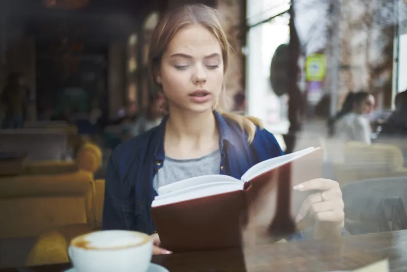 Женщина читает книгу в кафе, отдых, образ жизни, чашка кофе утром