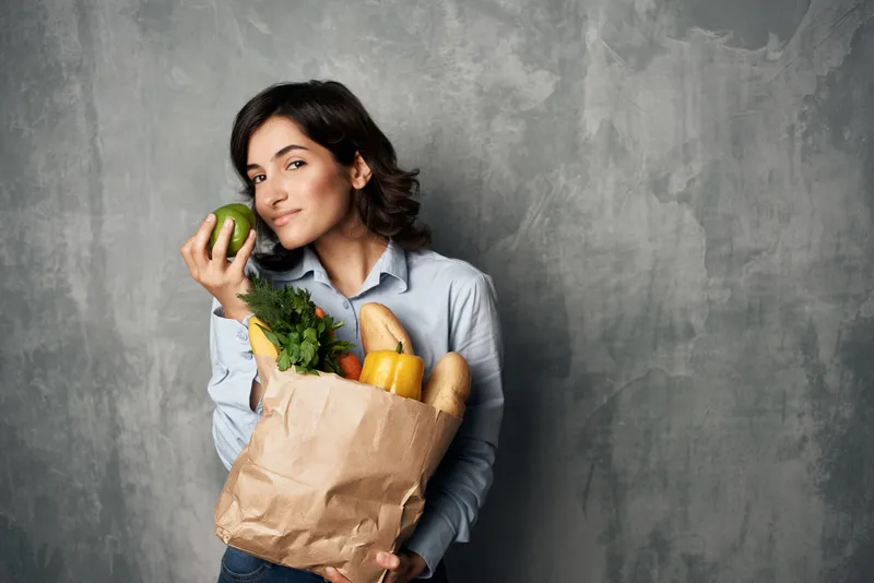 Женщина с пакетом продуктов, овощей, здоровой едой на тёмном фоне