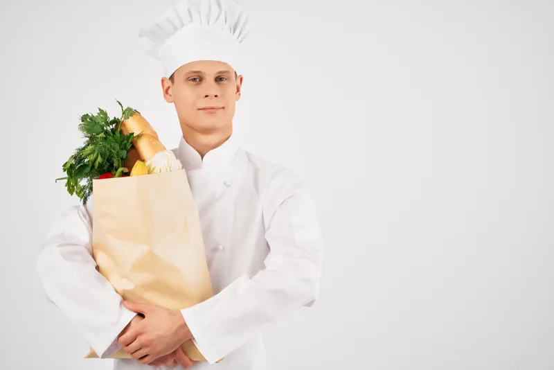 Повар-мужчина с пакетом продуктов в ресторане, профессионально занимающийся кулинарией