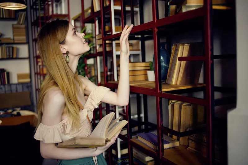 Весёлая женщина читает книгу в кафе, отдыхая