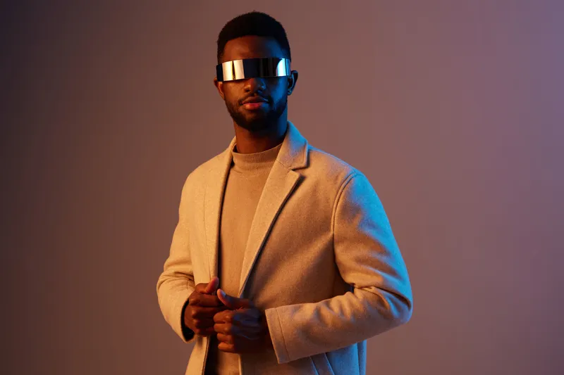 Stylish African man wearing futuristic sunglasses and a beige coat against a vibrant gradient background conveying a modern, confident look