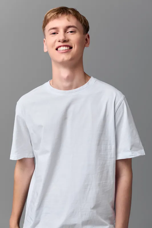Smile, tshirt, casual, young, man, studio, neutral, happiness captured in a clean shot suited for lifestyle, fashion, and wellness themes, showcasing a relaxed, approachable vibe in a simple white tee