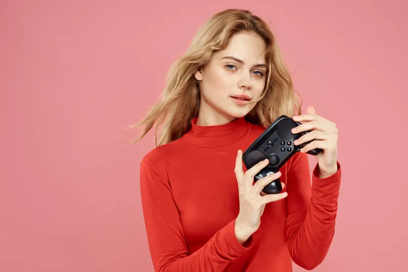 Женщина с геймпадом в руке, развлечения, видеоигры, образ жизни, технологии, красная блузка, розовый фон