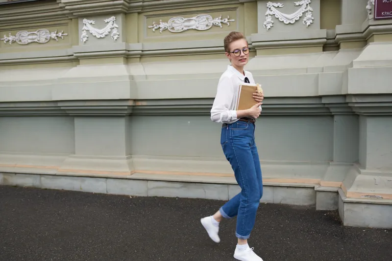 Студент в очках гуляет по городу с книгой, общаясь