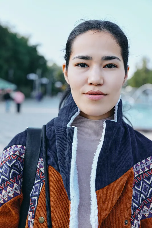 Woman wearing a knit jacket outdoors on a street with a calm confident expression, urban fashion, candid daytime style and relaxed mood