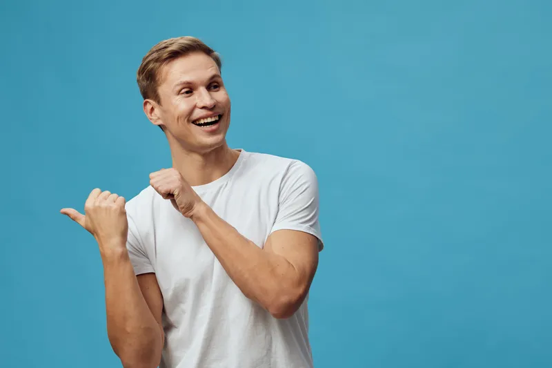 Smiling young man with short hair in casual white t-shirt on a bright blue background, expressing happiness and positivity, cheerful mood, studio portrait, lifestyle concept.
