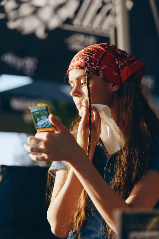 Lifestyle woman in modern boho-western denim street style applying skincare with a cotton pad, captured in warm natural light and film color tones.