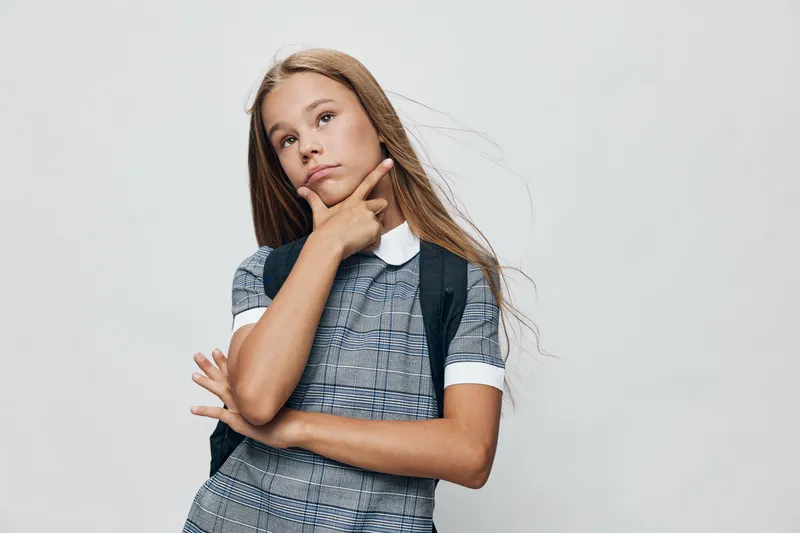 Girl, child and thoughtful with backpack standing isolated on white background. Blonde kid, casual outfit and confident pose for education, school or learning concept.