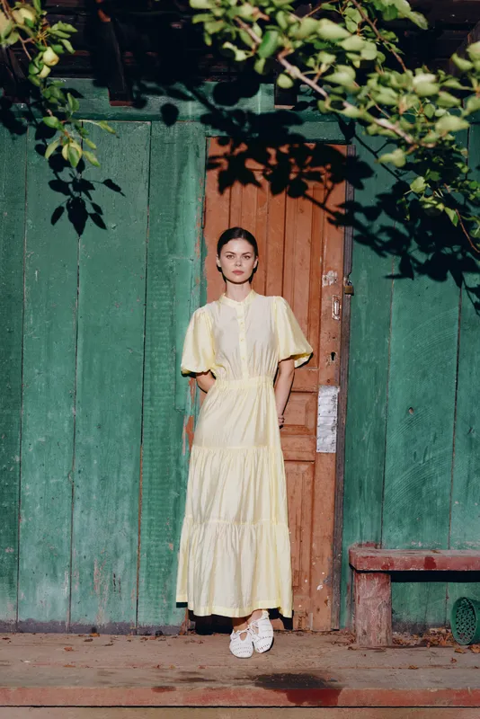 Woman portrait in yellow dress by rustic door, authenticity
