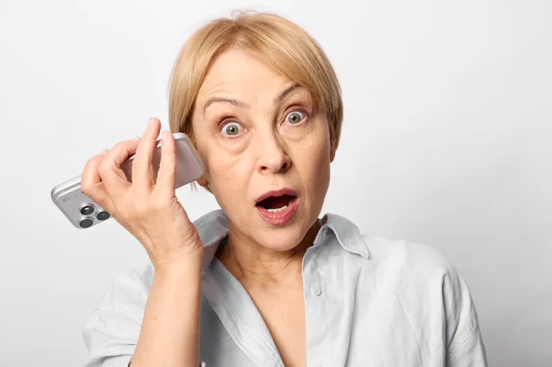 Woman surprised, holding phone to her ear, closeup portrait in studio with white background, instant communication and startled reaction, phone call, modern lifestyle today