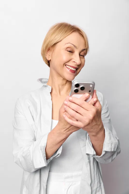 Elderly woman smartphone smiling communication technology portrait white message social, holding phone reading message, white background, relaxed expression, online chat