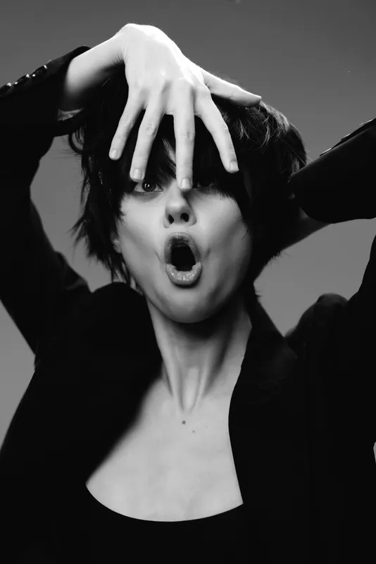 Black and white portrait of surprised woman with short hair and expressive face in dark jacket