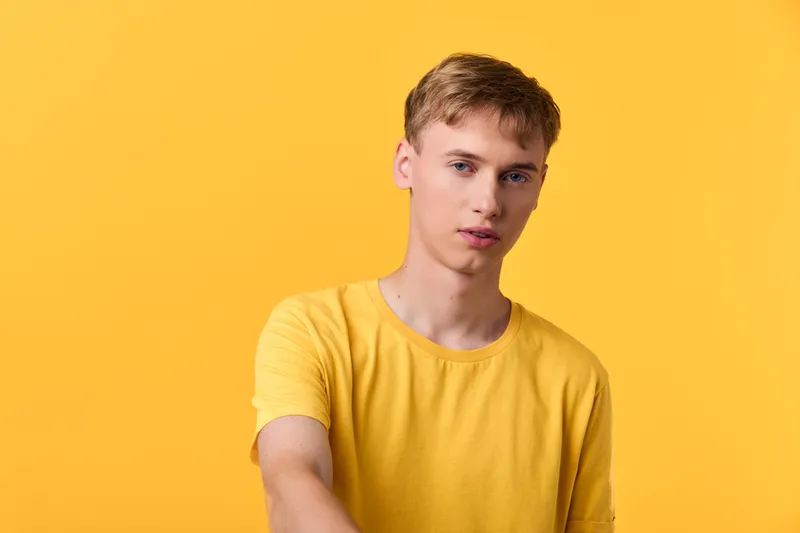 Young man in a yellow shirt against a yellow background, casual pose, studio lighting creates a clean lifestyle shot suitable for fashion, advertising, and product campaigns, with versatile