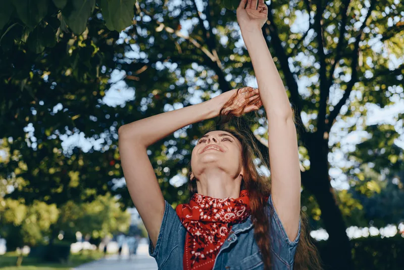 lifestyle woman in modern boho-western denim street style enjoying sunny day with film color tones and vibrant natural background in outdoor urban environment