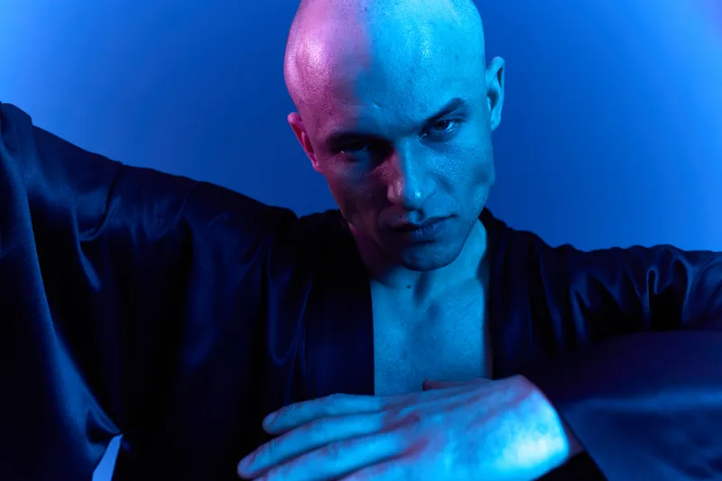 Intense man with a focused expression, showcasing determination and strength in a vibrant blue light. A dynamic portrayal emphasizing emotion and character depth.